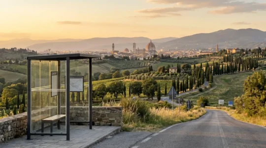 Wide panoramic view of rolling Tuscan hills with Florence's Duomo visible in the distant skyline, a clean modern bus shelter in the foreground under warm golden hour lighting
